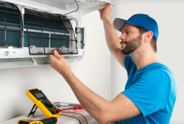 Installation service fix  repair maintenance of an air conditioner indoor unit, by cryogenist technican worker checking the air filter in blue shirt and baseball cap